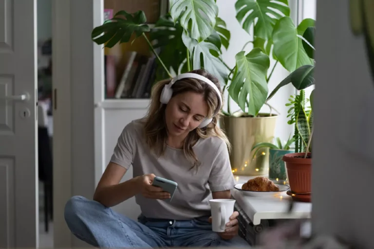 Ragazza che ascolta la musica con le cuffie e una tazza di caffè in mano