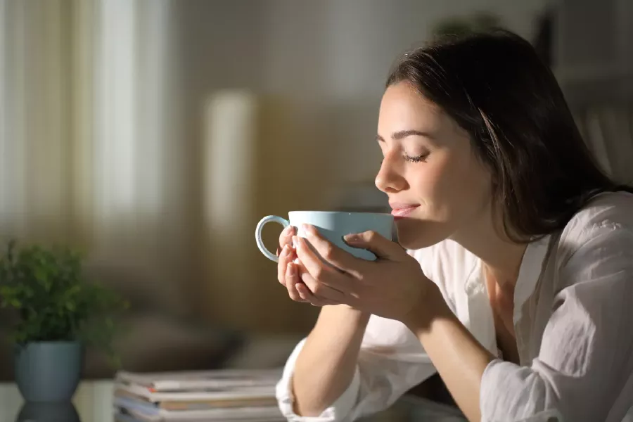 Ragazza che annusa una tazza di caffè fumante