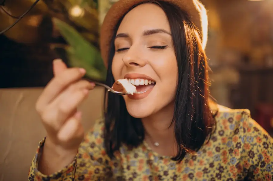 Ragazza che gusta un assaggio di tiramisù al caffè con aria soddisfatta