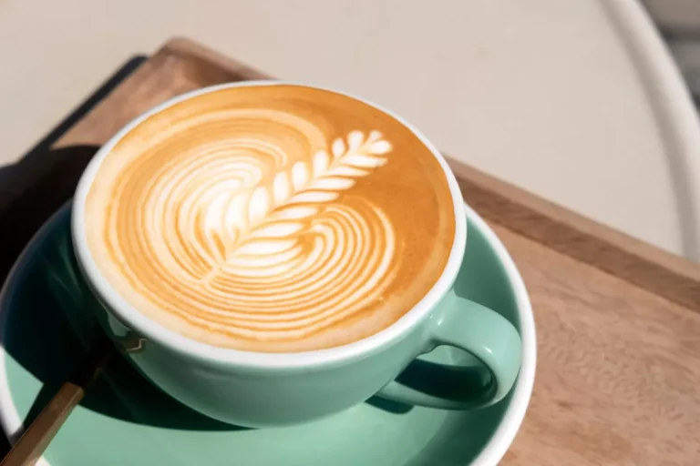 Tazza verde con cappuccino con schiuma perfetta e decorata