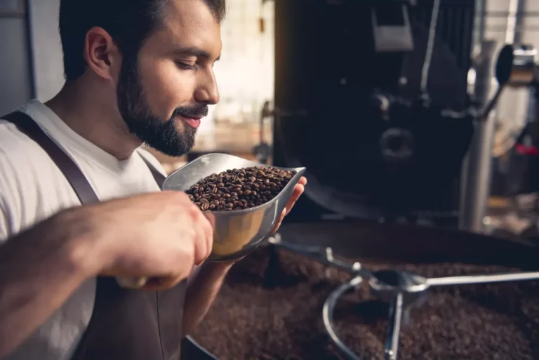 Torrefattore che annusa con gli occhi chiusi i chicci di caffè artigianale