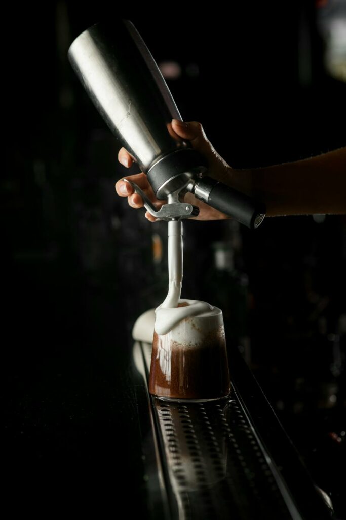 Cocktail al caffè decorato con spuma dal sifone, tutto su sfondo nero