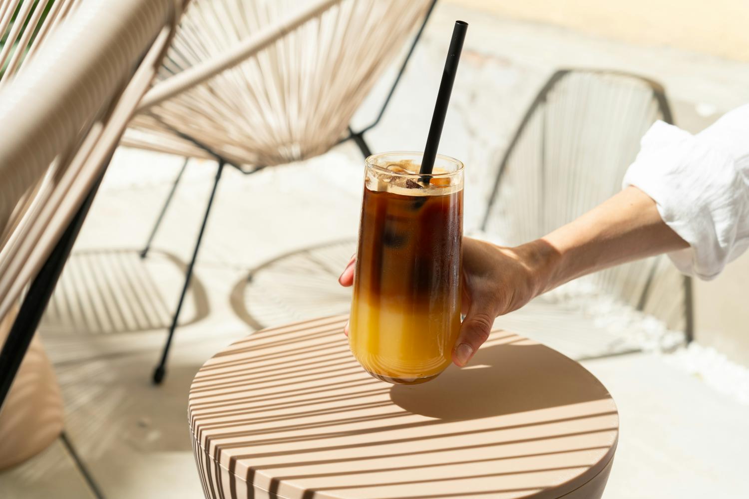 Cocktail al caffè su un tavolino, con il braccio di una ragazza che afferra il bicchiere