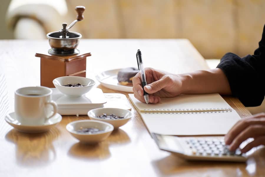 scrivania con persona che lavora con caffè, calcolatrice, macinino