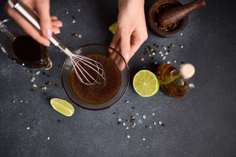 Prospettiva dall'alto su piano con mano che tiene una frusta per amalgamare la marinatura al caffè