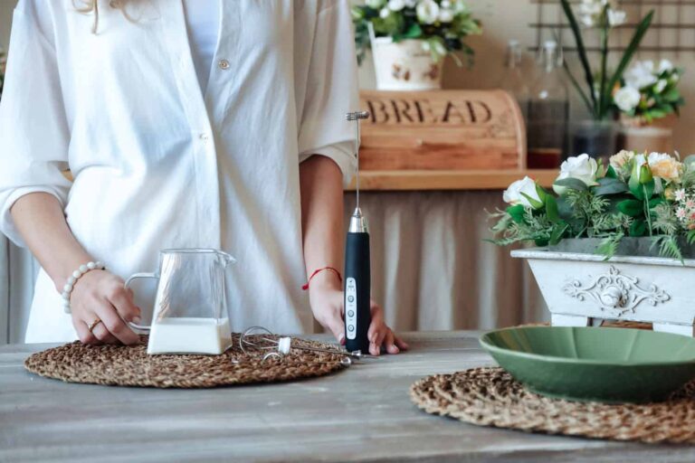 Figura umana con un tavolo ricco di oggetti tra cui un cappuccinatore manuale