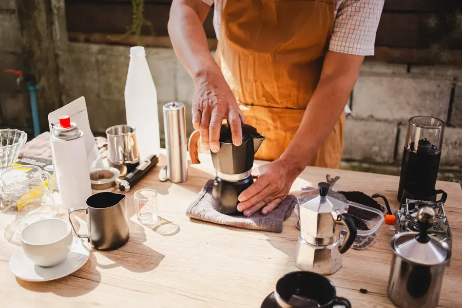 tavolo con tante caffettiere e una persona che le maneggia
