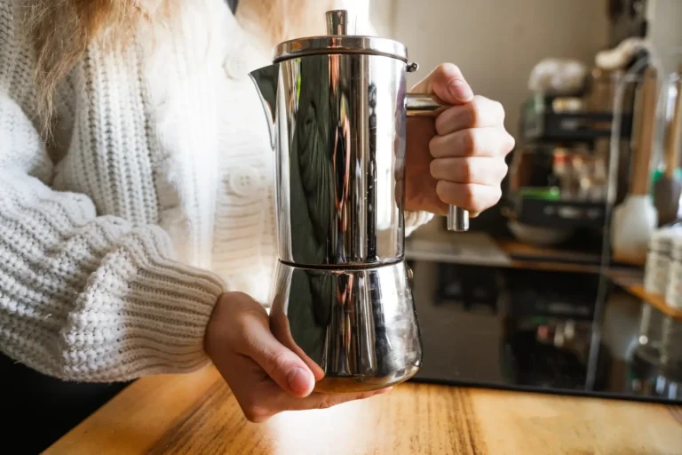 caffettiera in primo piano tenuta da sopra e sotto