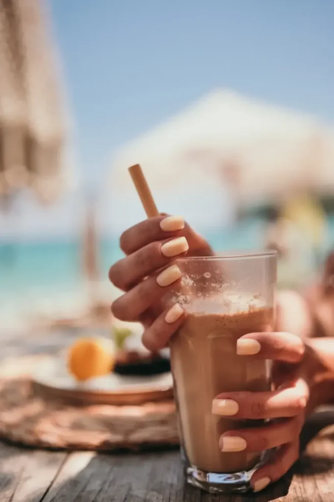 Cocktail al caffè estivo con sfondo mare e ombrelloni